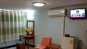 A hotel room with a wooden desk, a chair, a small refrigerator, a TV mounted on the wall, and a window with curtains. - Rongkhem-City Hotel (Rong Kwang)