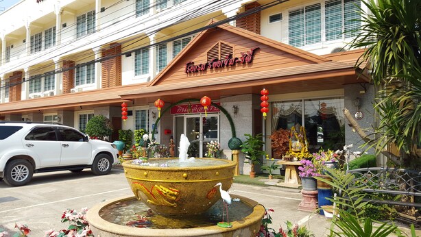 A hotel with a traditional Thai architectural style, a large decorative fountain, and a white car parked in front. - Rongkhem-City Hotel (Rong Kwang)
