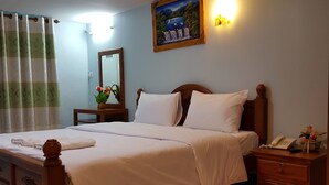 A neatly made bed with white linens, a wooden headboard, and a bedside table with a lamp and a vase of flowers. - Rongkhem-City Hotel (Rong Kwang)