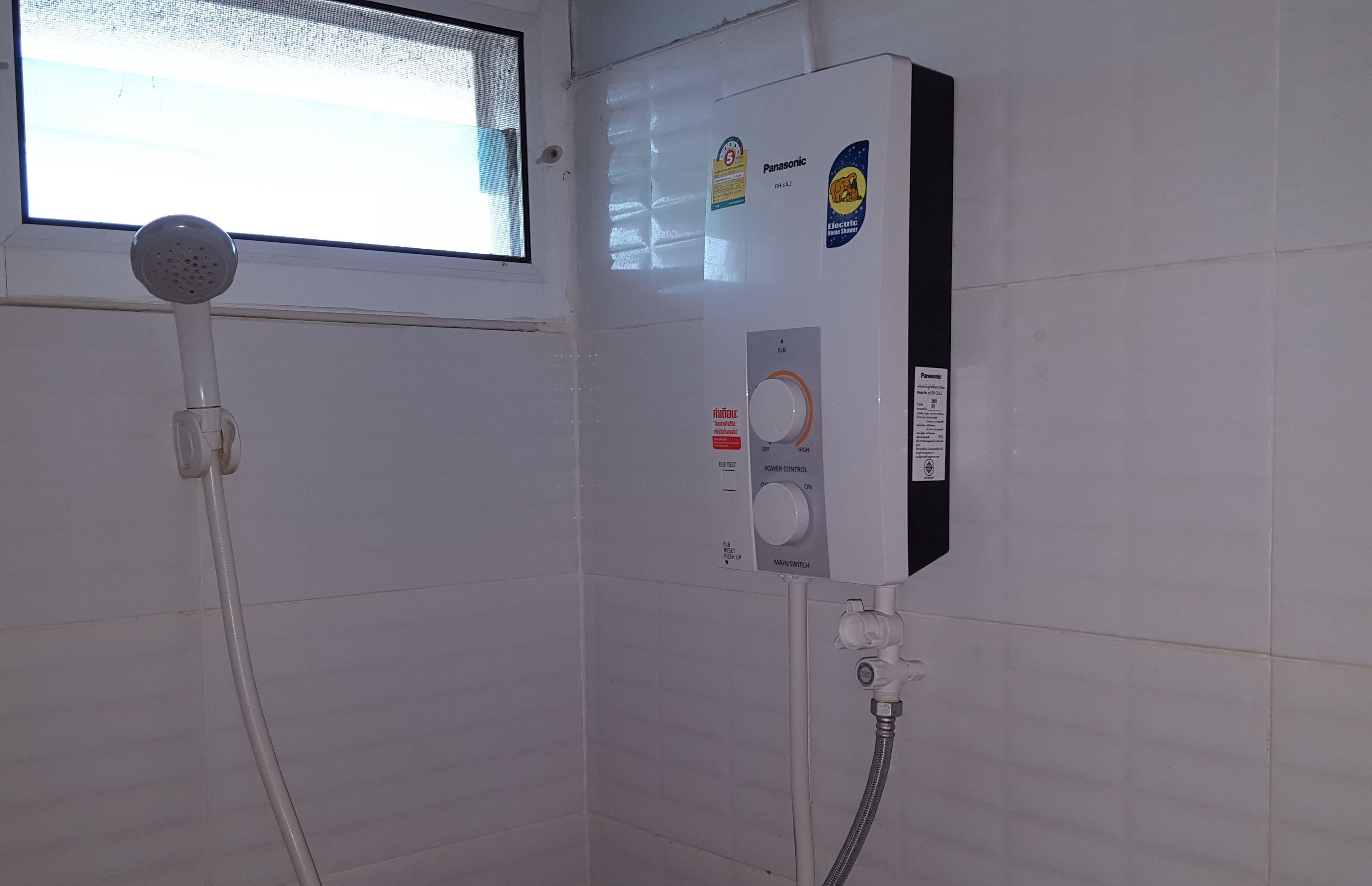 Une salle de bain avec une douche, une fenêtre et un chauffe-eau Panasonic.