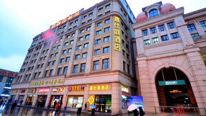A multi-story hotel with a prominent sign on the facade, multiple ground-level retail spaces, and a large arched entrance. - Jiashiting Hotel Hankou Railway Station (Wuhan)