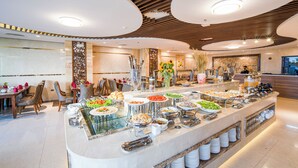A buffet with various food items and a seating area with chairs and tables. - Luxtery Hotel (Da Nang)
