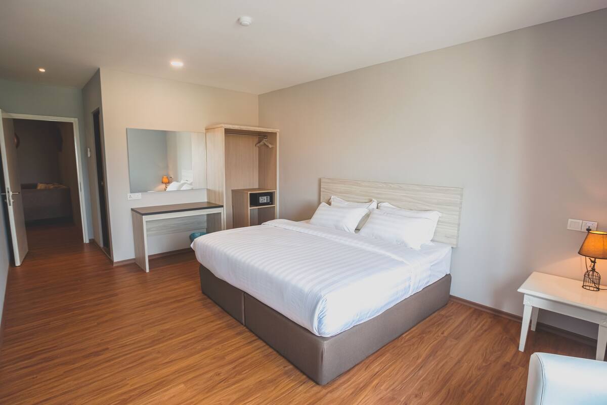 Une chambre d’hôtel moderne, dotée d’un grand lit, d’un bureau, d’une armoire et d’une table de chevet avec une lampe.