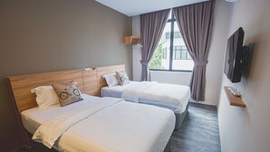 Een hotelkamer met twee bedden, een televisie en een raam met gordijnen.