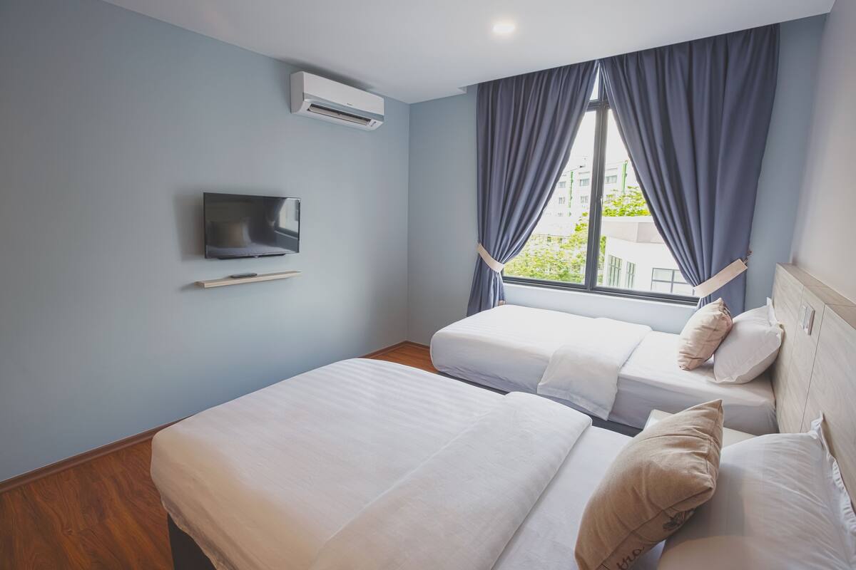 Une chambre d’hôtel avec deux lits, une télévision et une fenêtre avec des rideaux.