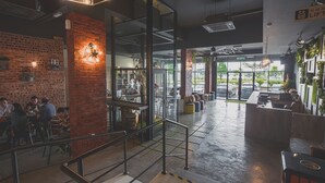 Een ruim café met een bakstenen muur, een trap en een bar.