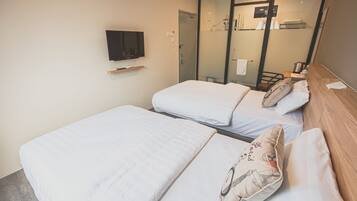 A hotel room with two beds, a TV on the wall, and a sliding door leading to a bathroom.
