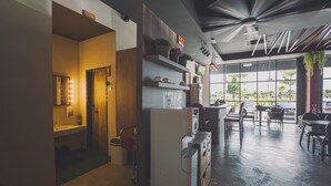 Een modern interieur met een keukenhoek, een zithoek met tafels en stoelen, en een groot raam met uitzicht op de omgeving.