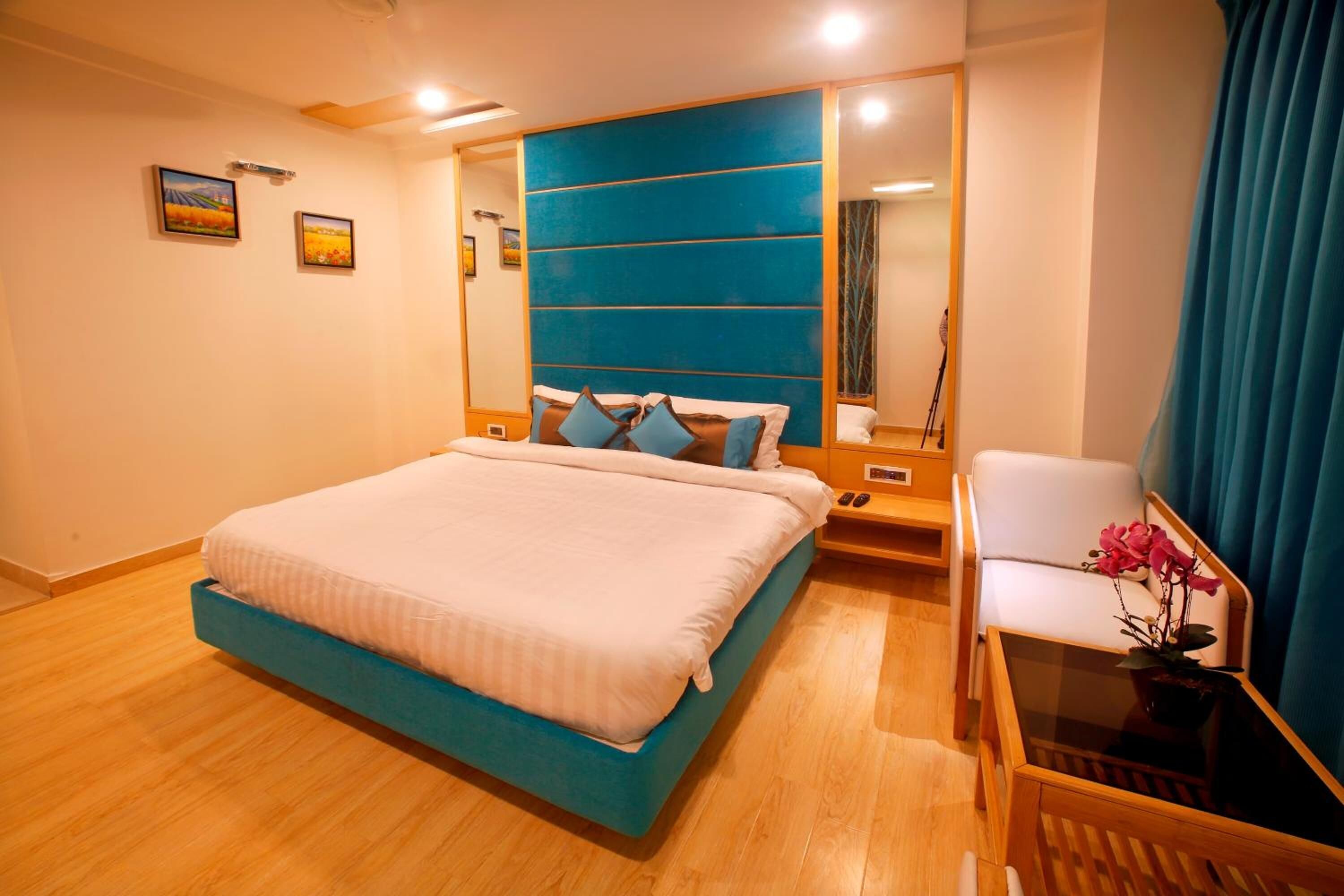 A modern bedroom with a large bed, a bedside table, a chair, and a mirror.