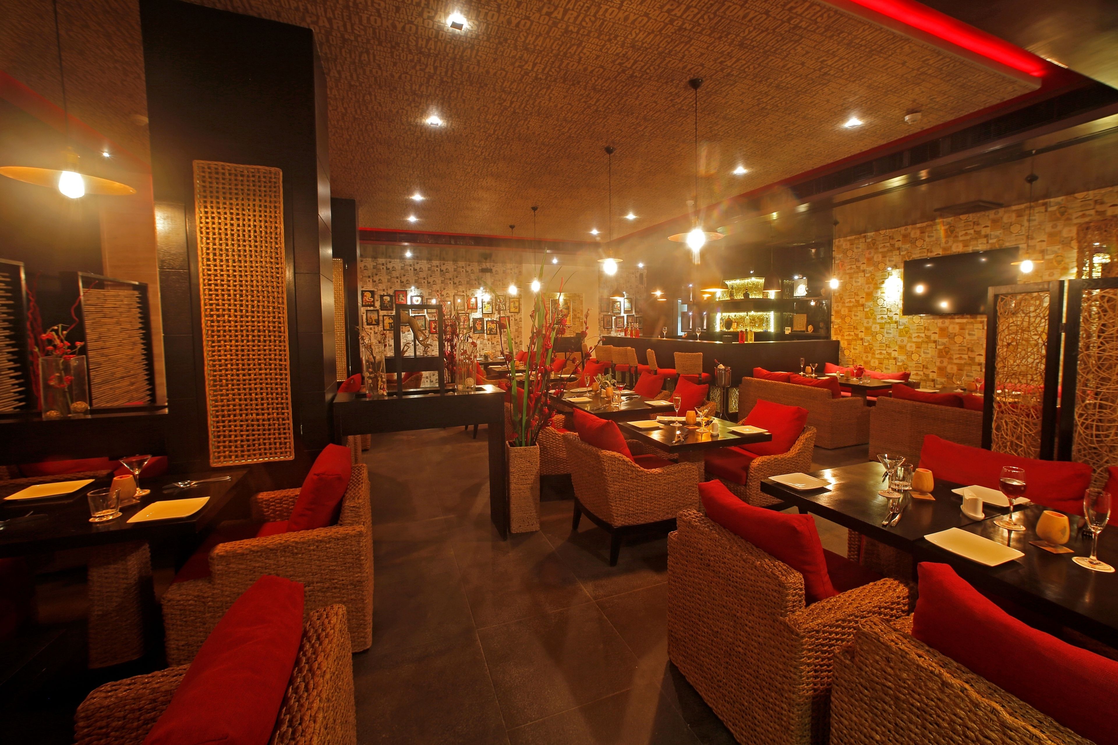 A restaurant with wicker furniture, red cushions, and a brick wall.