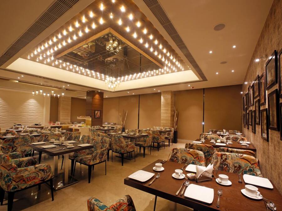 Un comedor amplio con múltiples mesas y sillas, un candelabro y obras de arte enmarcadas en las paredes.