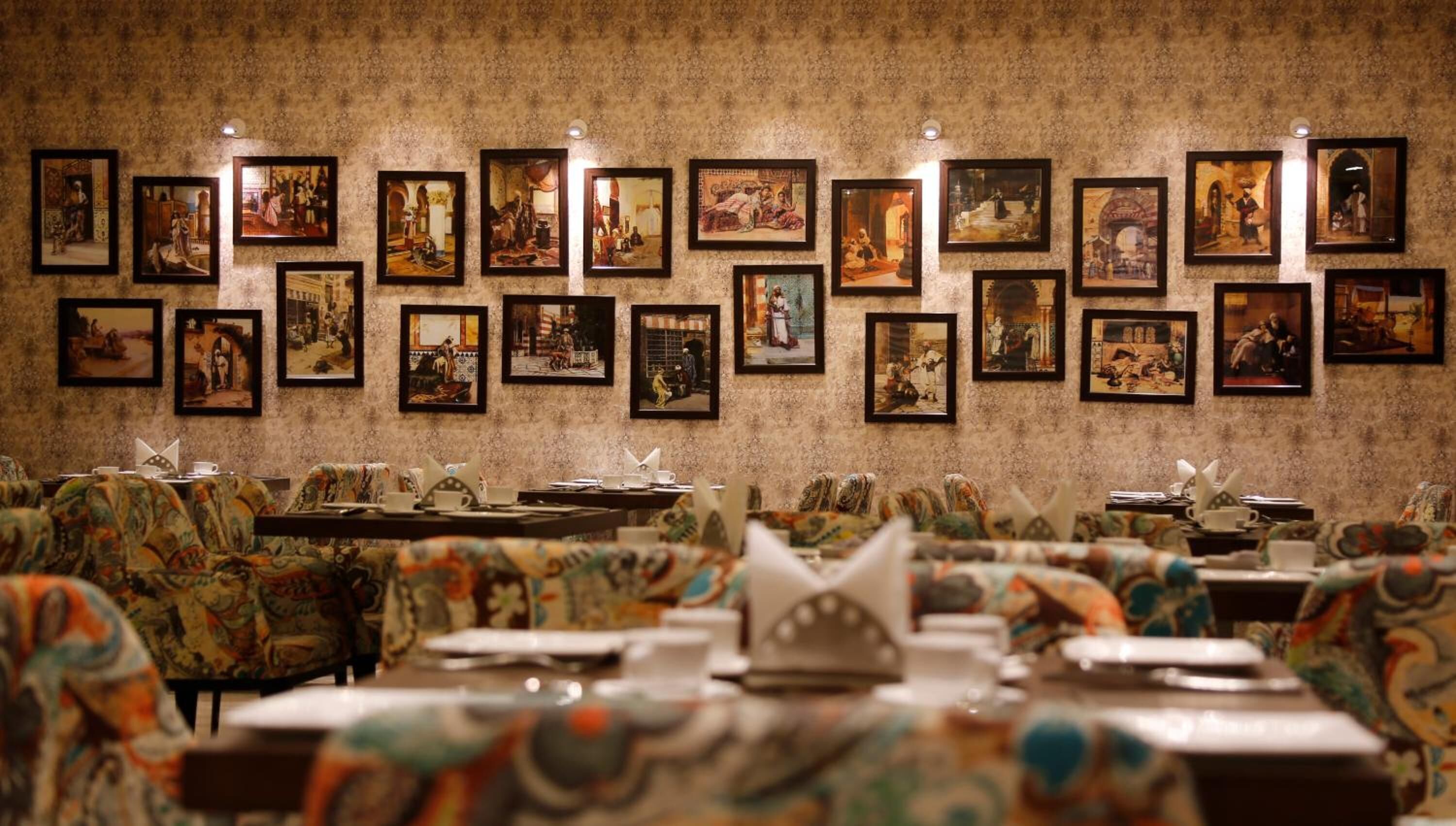 Een restaurant met gestreept meubilair en kunstwerken in lijsten aan de muur.