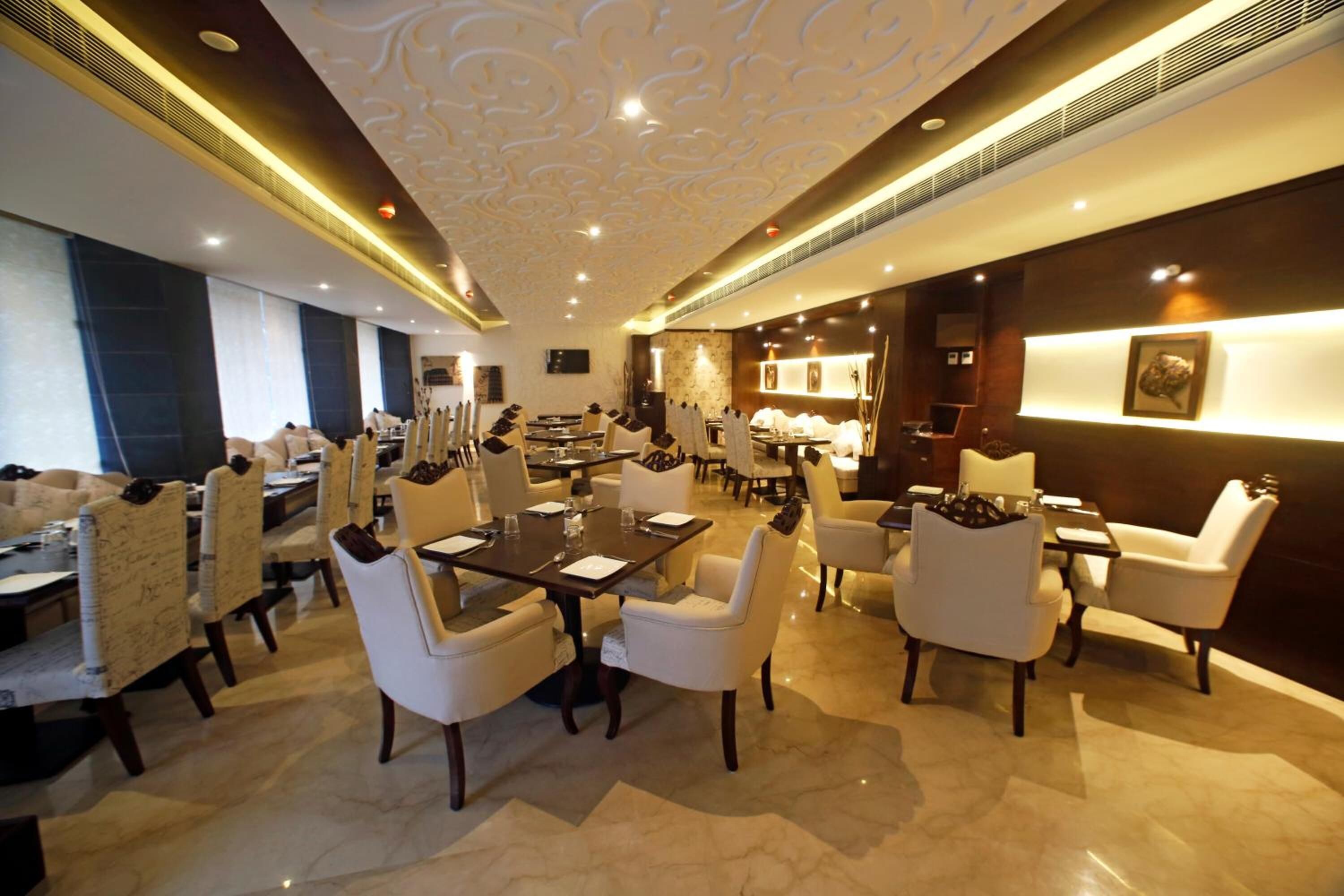 A spacious hotel lobby with a high ceiling, marble flooring, and a mix of dining and seating areas.