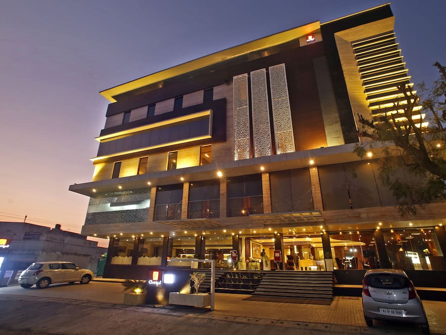 A multi-story hotel with a modern design, featuring a prominent entrance with steps and a covered area.