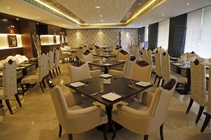 Un comedor de hotel con varias mesas y sillas, cada una con un mantel individual y cubiertos.