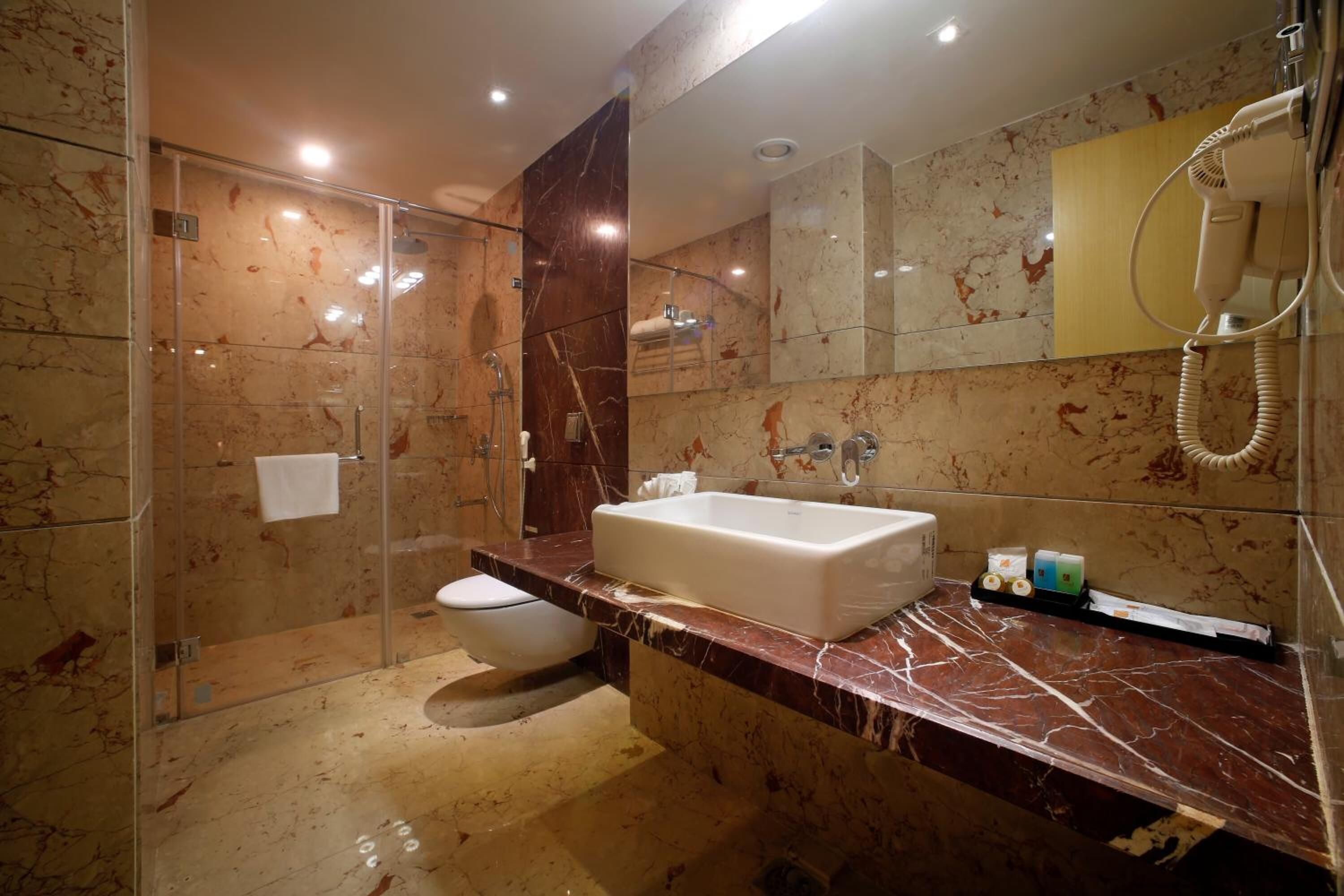 A modern bathroom with a glass-enclosed shower, a marble vanity, and a large mirror.