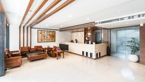 A modern reception area with a wooden reception desk, seating arrangements, and a large abstract painting on the wall. - Hotel LN Courtyard (Ajmer)