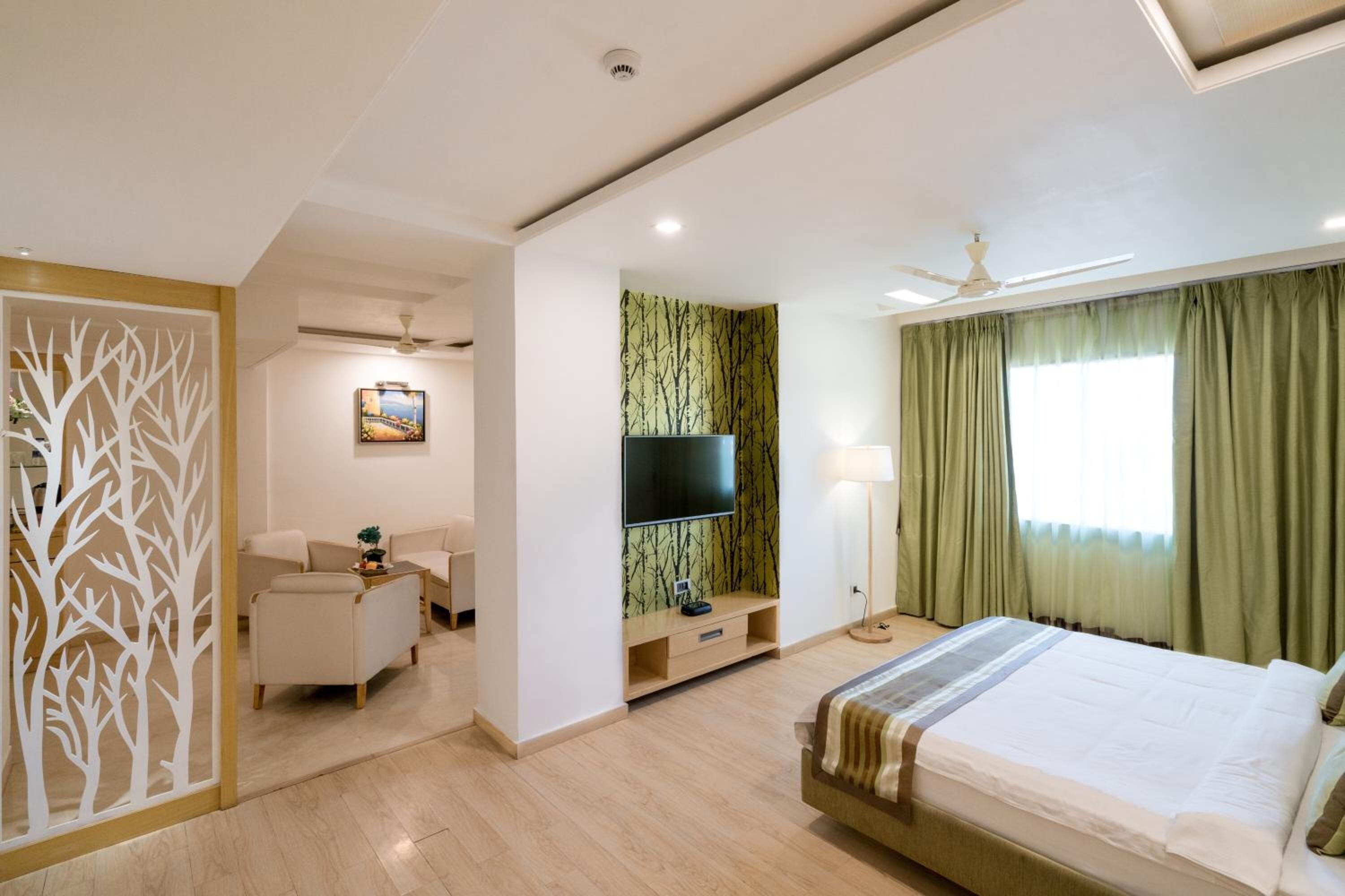 A modern hotel room with a bed, a TV, a desk, and a chair.