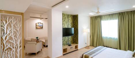 A modern hotel room with a bed, a TV, a desk, and a chair.