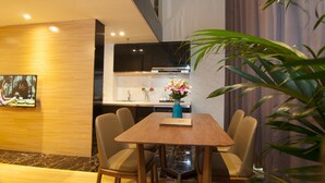 Un espace de repas moderne avec une table et des chaises en bois, un vase de fleurs et une cuisine en arrière-plan.