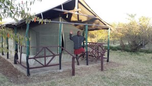 A person standing in front of a tent-like structure with a metal frame and a roof. - Destiny Eco Camp (Maasai Mara)