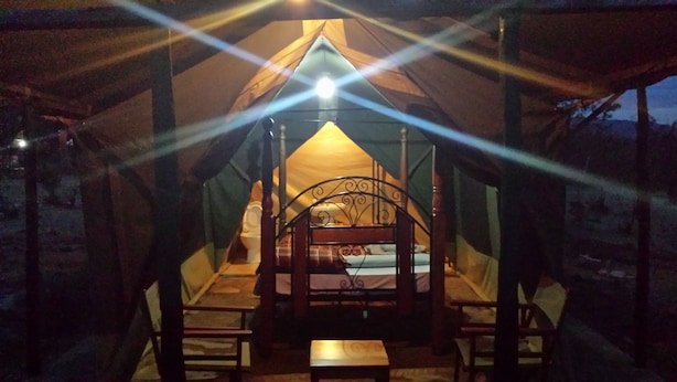A tent with a bed, a table, and chairs inside. - Destiny Eco Camp (Maasai Mara)