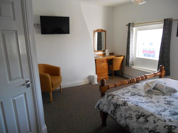 A bedroom with a bed, a chair, a desk, a dresser, a mirror, and a TV on the wall. - Yarm View Guest House and Cottages (Yarm)
