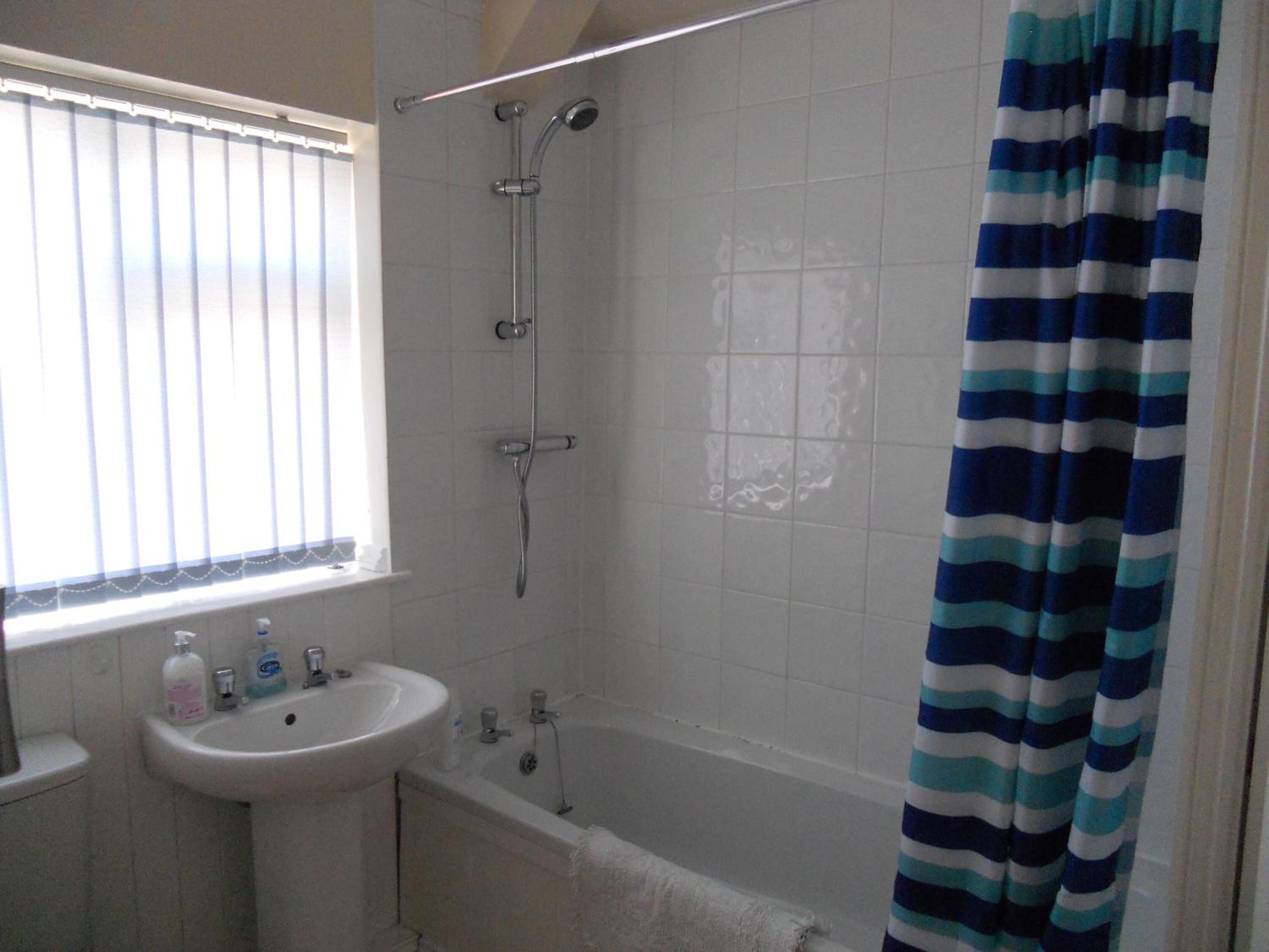 Un baño con un lavamanos blanco, una bañera y una ducha.