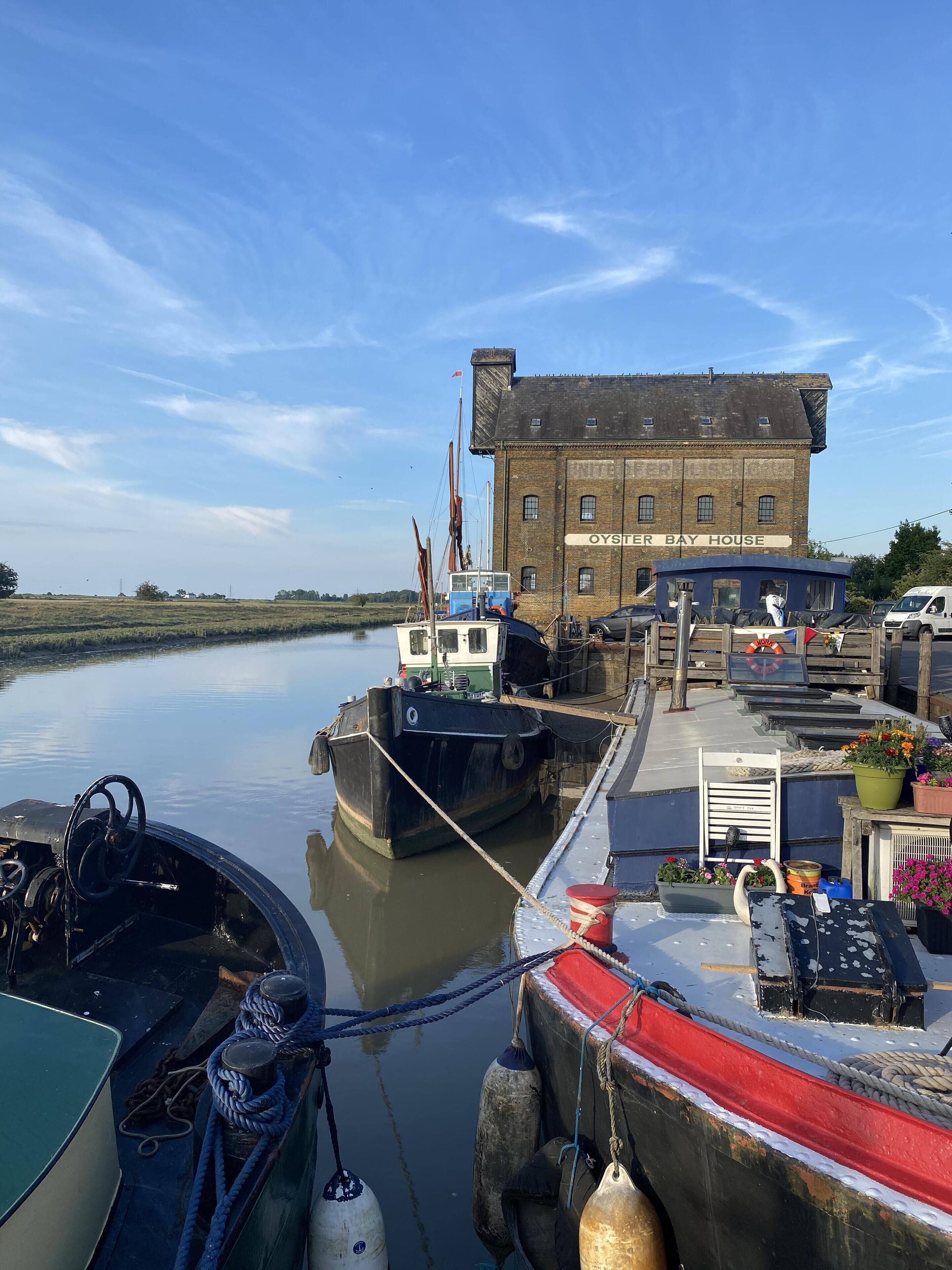 A dock with boats, a building labeled "Oyster Bay House," and a calm river.