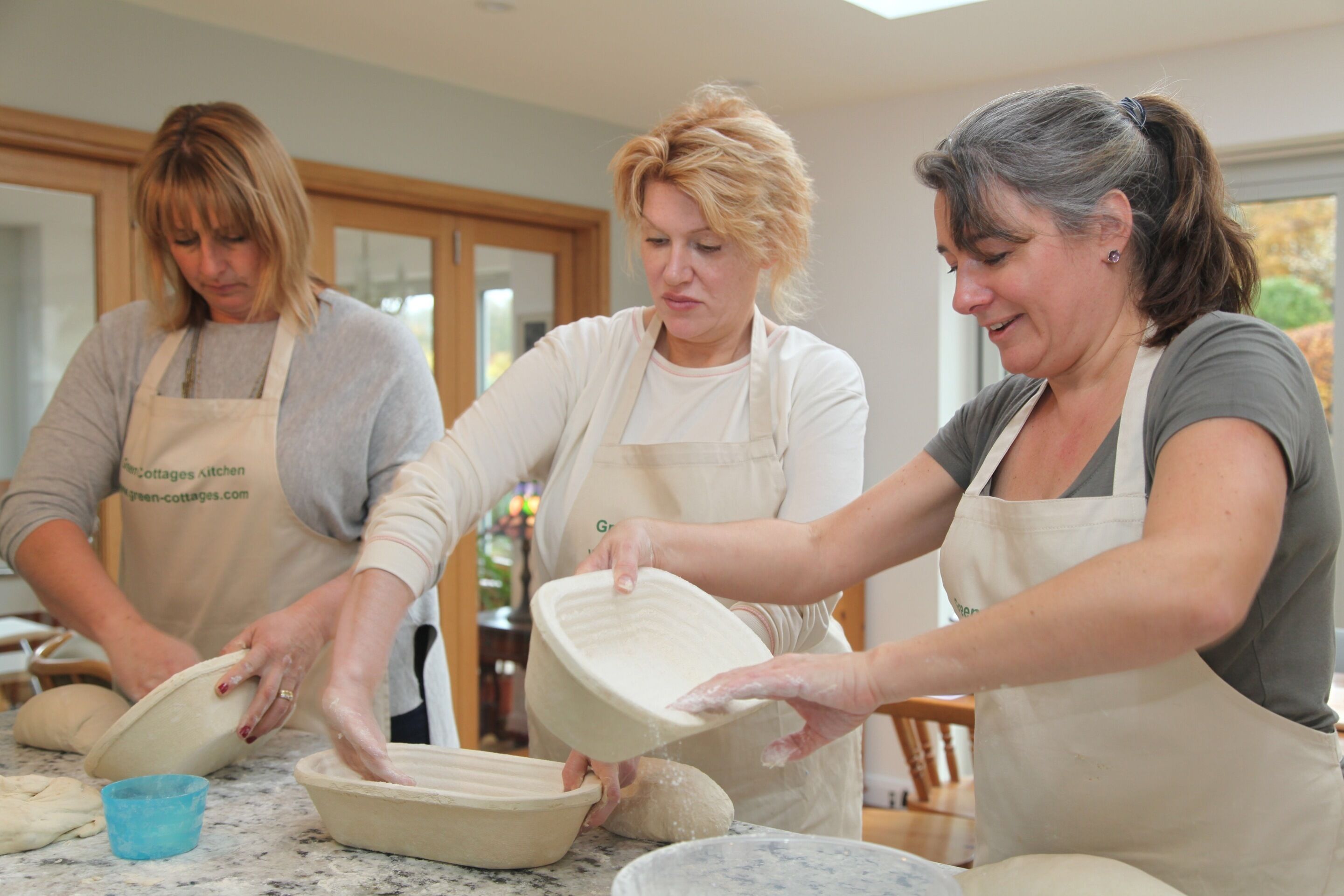 Tres personas en una cocina preparando comida, con delantales.