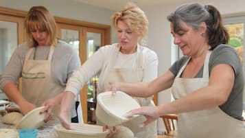 Tres personas en una cocina preparando comida, con delantales.