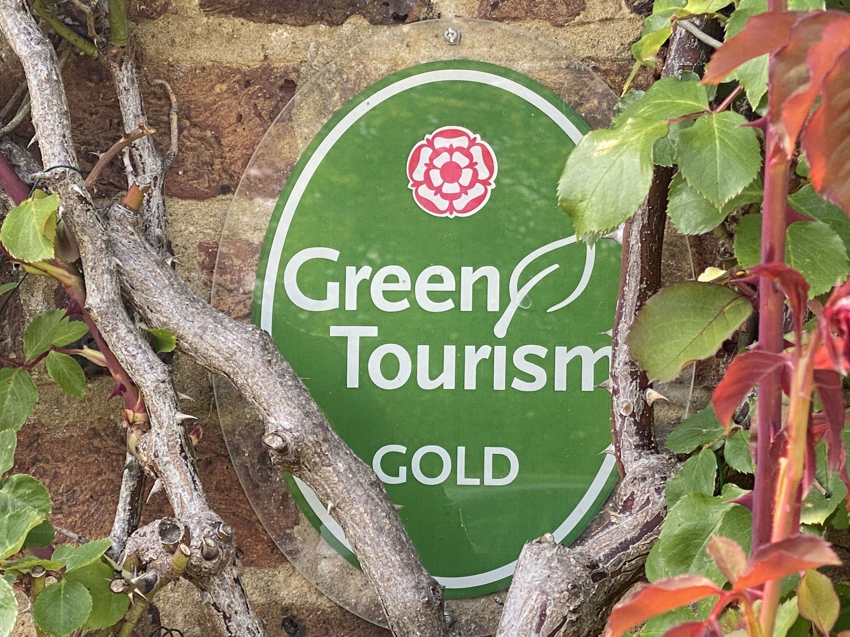 A green sign with the text 'Green Tourism GOLD' and a red flower emblem.