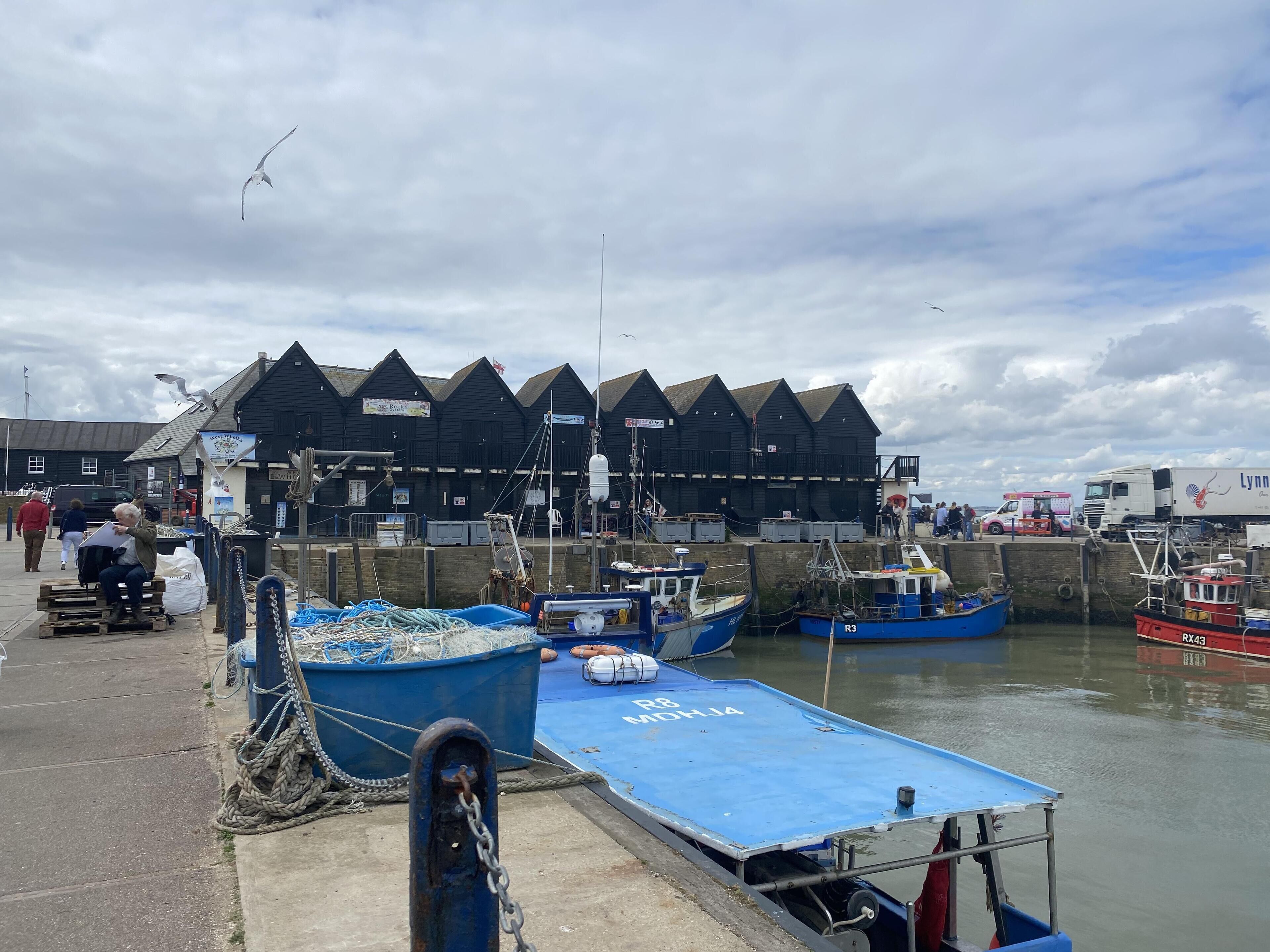 A harbor with boats docked, a pier, and a building with a pointed roof.