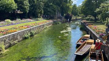 Un canal con barcos, rodeado de abundante vegetación y macizos de flores.