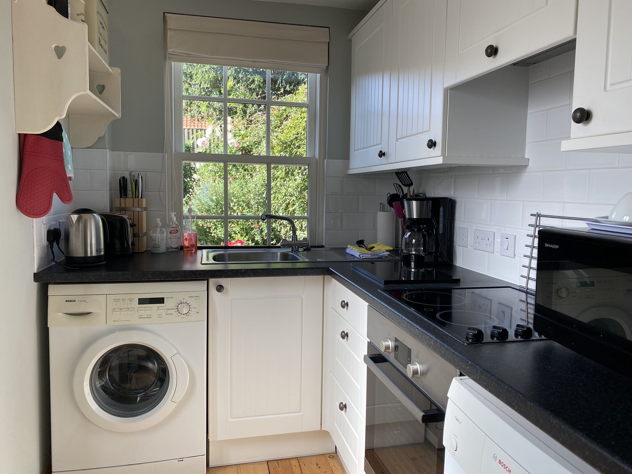 A modern kitchen with a Bosch dishwasher, a coffee maker, and a Sharp microwave.