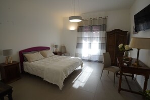 A bedroom with a bed, bedside tables, a chair, a desk, a lamp, a wardrobe, and a TV on the wall. - B&B Bivona (Mazara del Vallo)