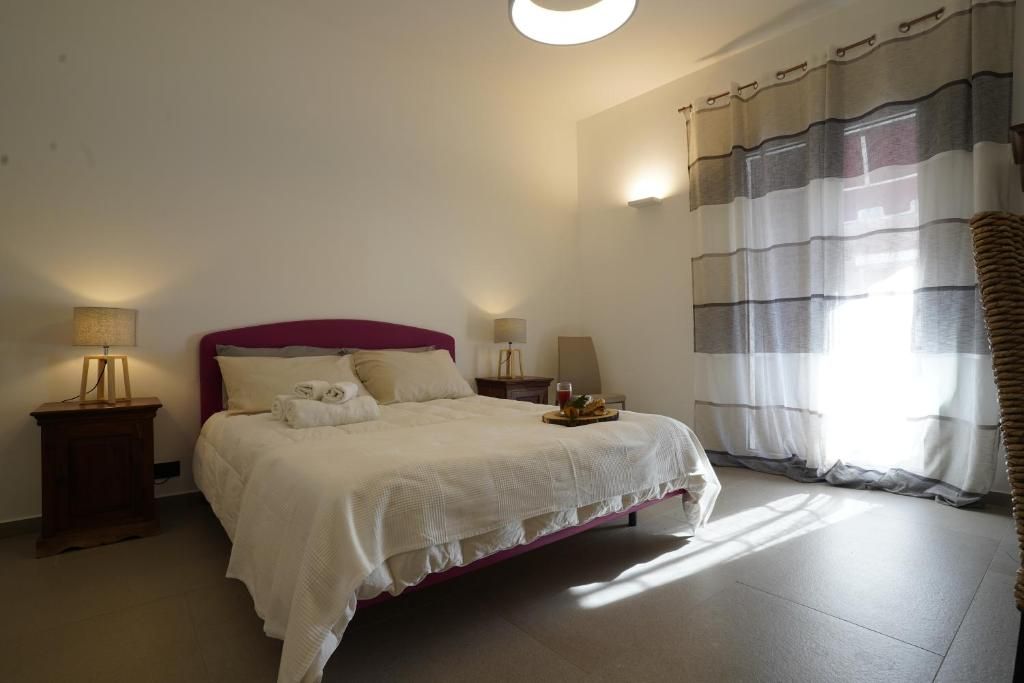 Una camera da letto con un letto, comodini, una lampada e tende.