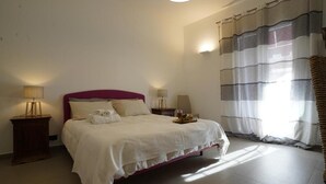 Un dormitorio con cama, mesitas de noche, lámpara y cortinas.