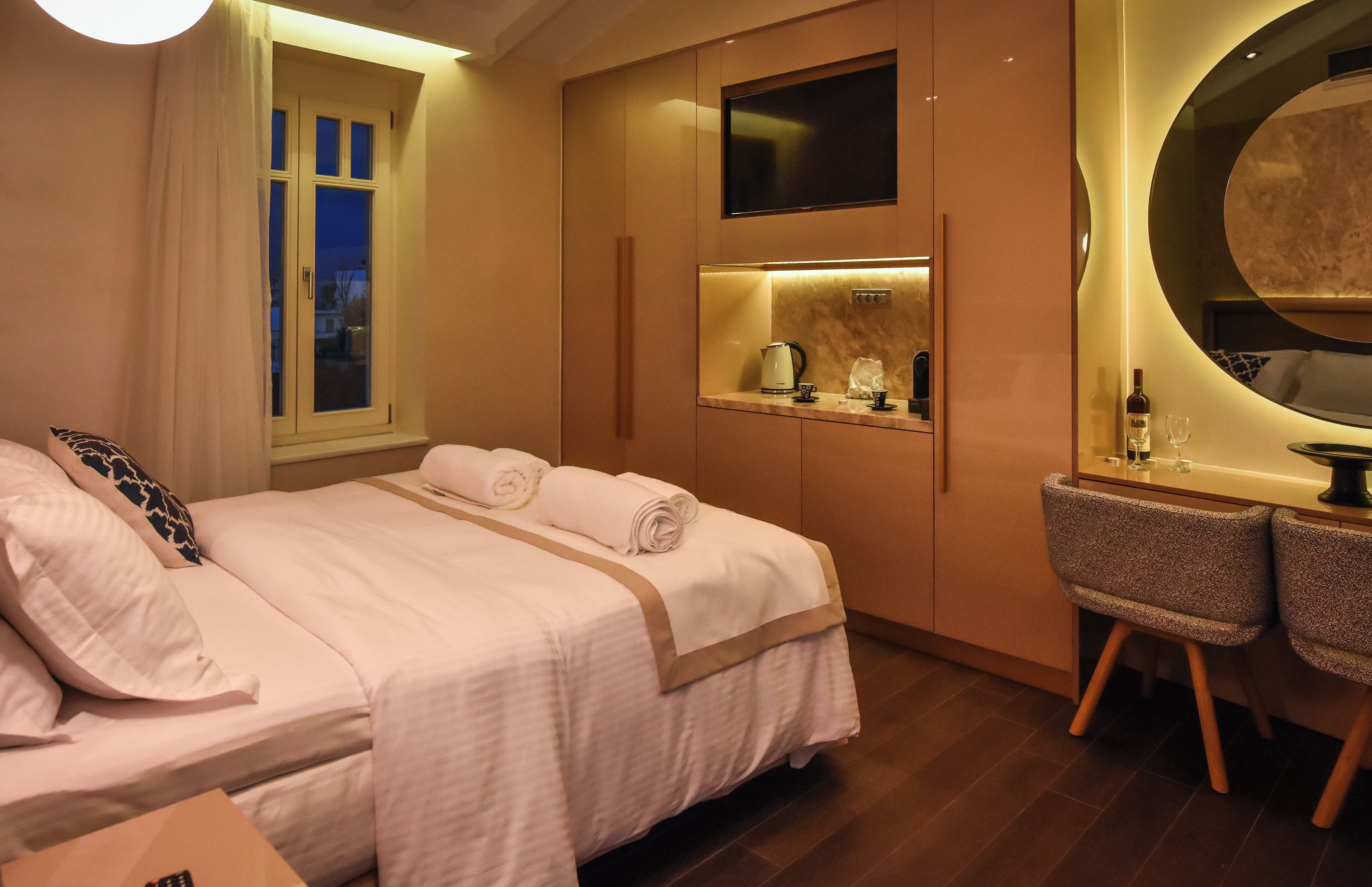 Een hotelkamer met een bed, een bureau, een stoel, een spiegel en een raam.