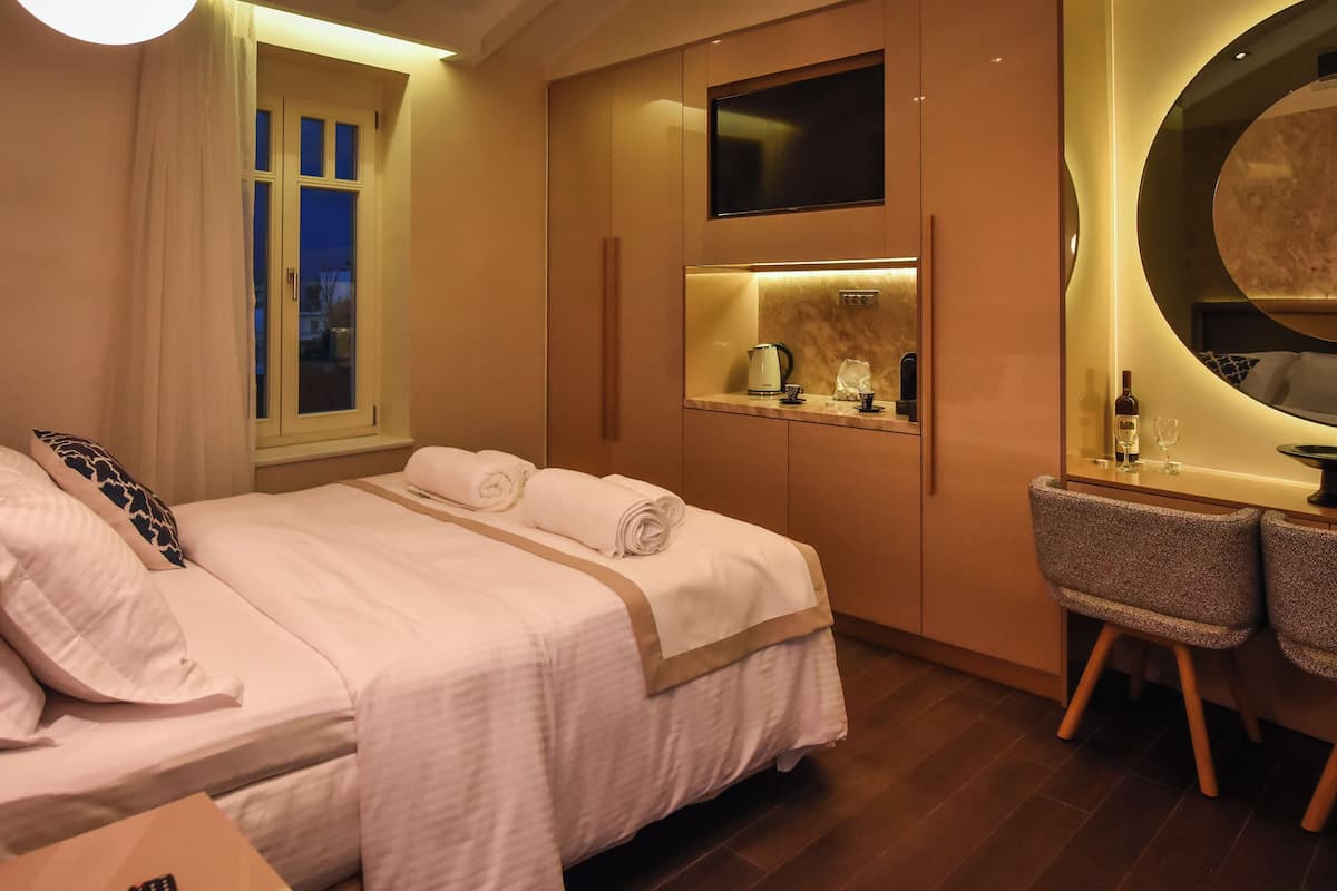 A hotel room with a bed, a desk, a chair, a mirror, and a window.