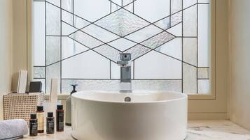 A bathroom with a white sink, a mirror, and toiletries on the counter.