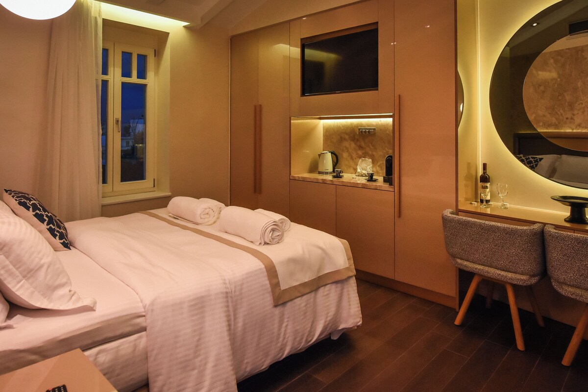 A hotel room with a bed, a desk, a chair, a mirror, and a window.