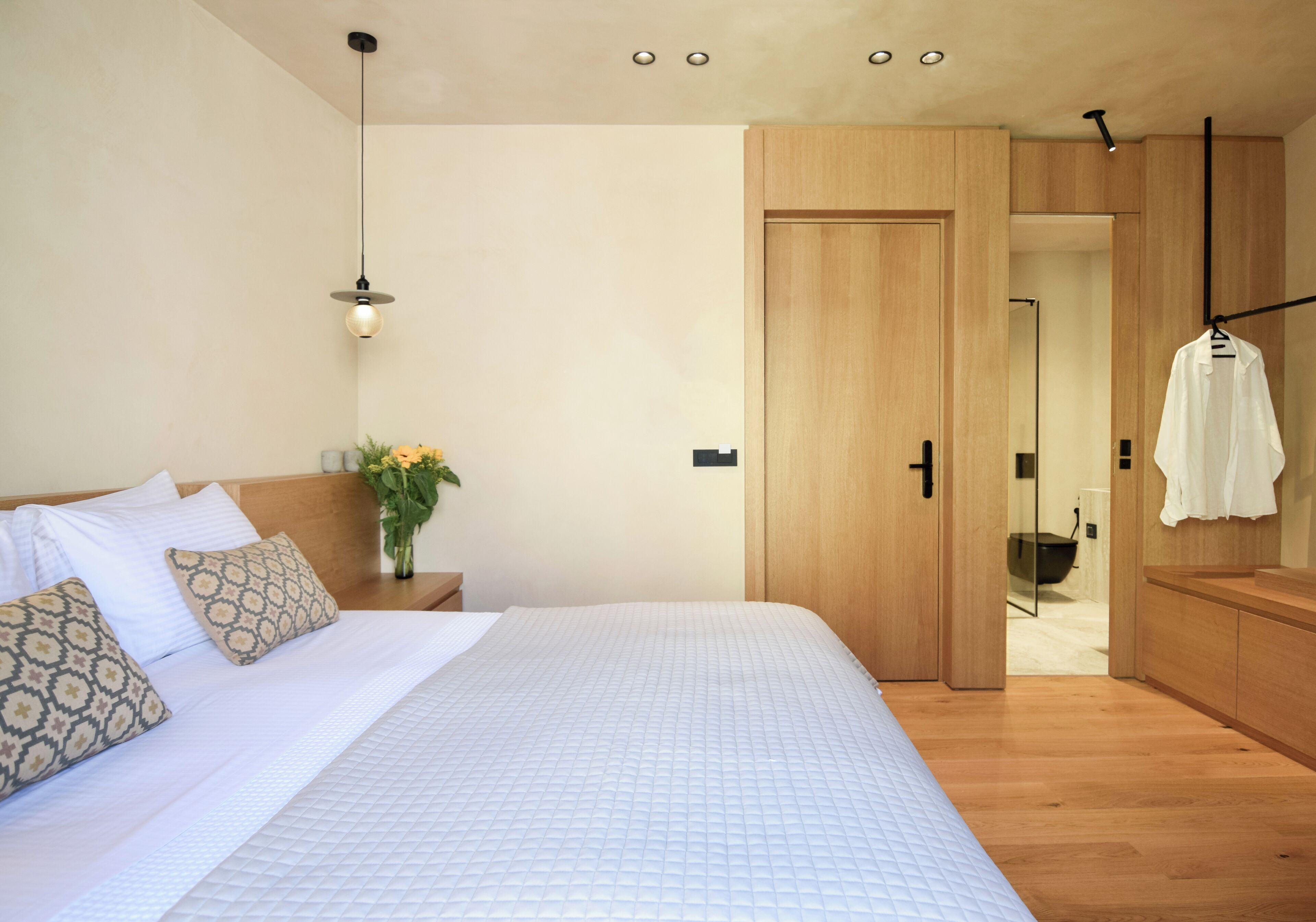Een slaapkamer met een groot bed, een houten kledingkast en een badkamer die door een geopende deur zichtbaar is.