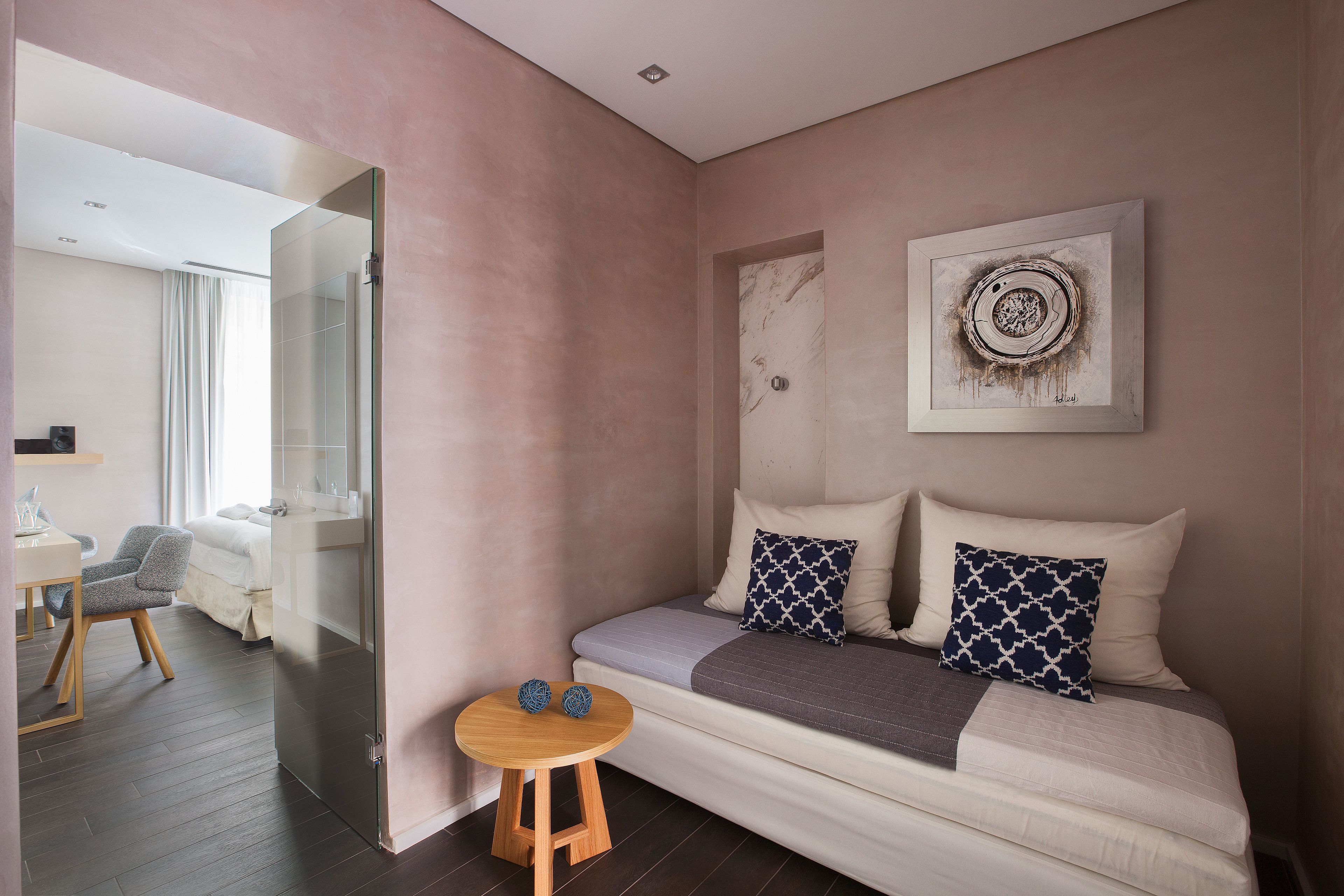 A modern bedroom with a sofa bed, a small wooden table, and a wall-mounted artwork.