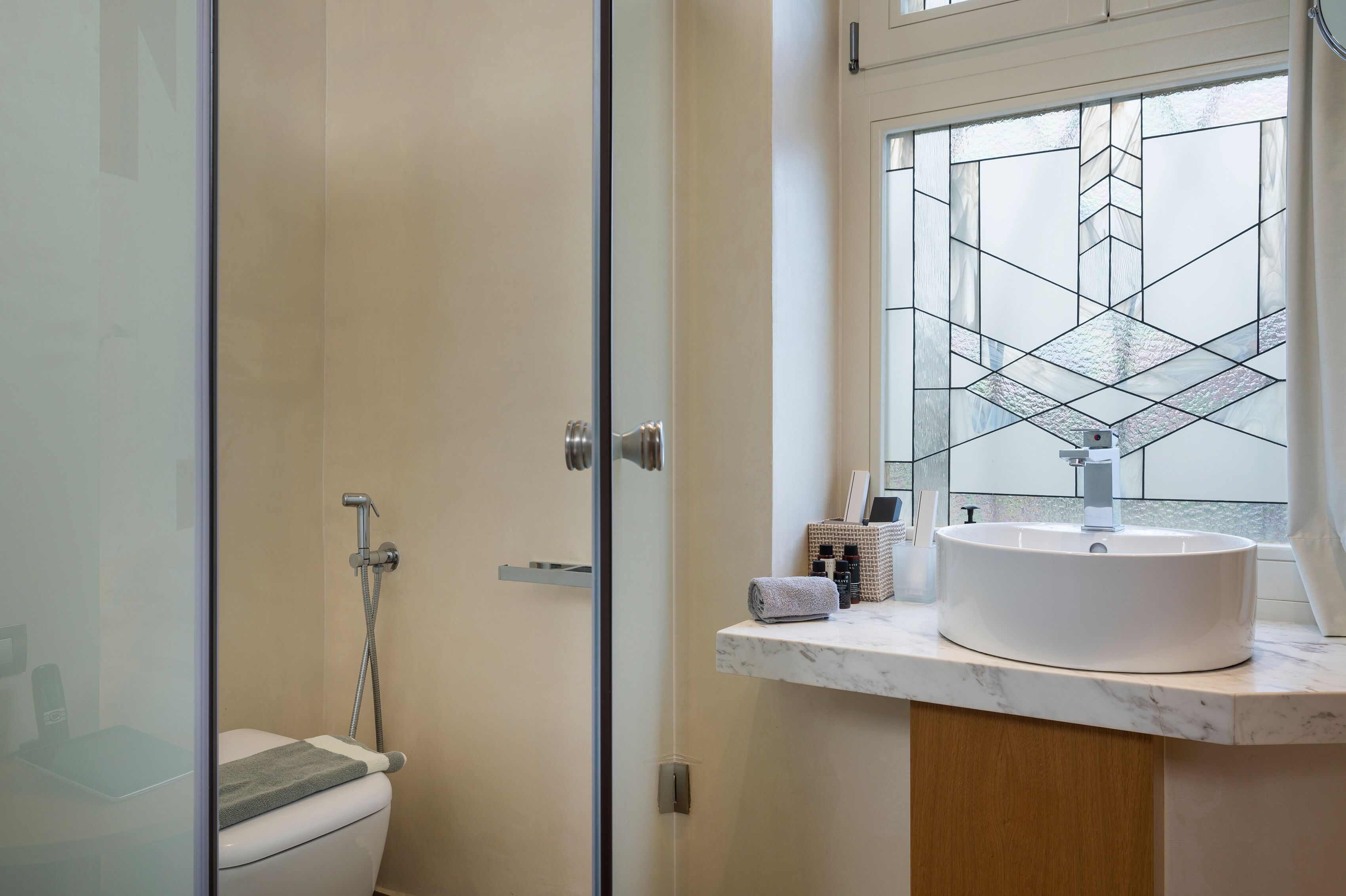 A modern bathroom with a toilet, a shower, and a sink with a marble countertop.