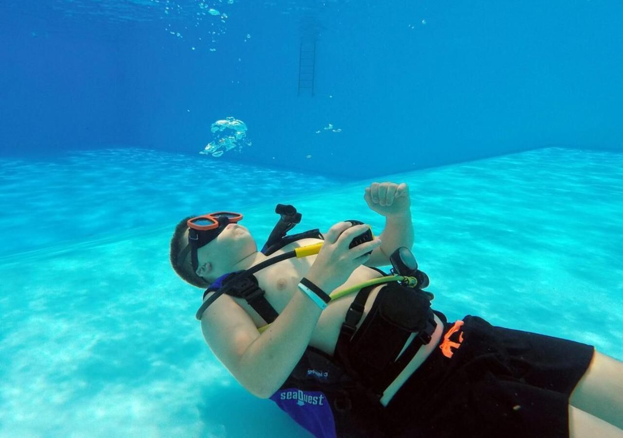 A person underwater in a pool, wearing a snorkel and fins.