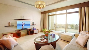 A modern living room with a flat-screen TV, comfortable seating, a glass coffee table, and large windows offering a view of the outdoors. - Roda Beach Resort (Dubai)