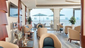 A modern lounge with comfortable seating, a glass table, and a view of the sea. - Roda Beach Resort (Dubai)