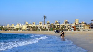 A beach with a row of buildings in the background. - Roda Beach Resort (Dubai)