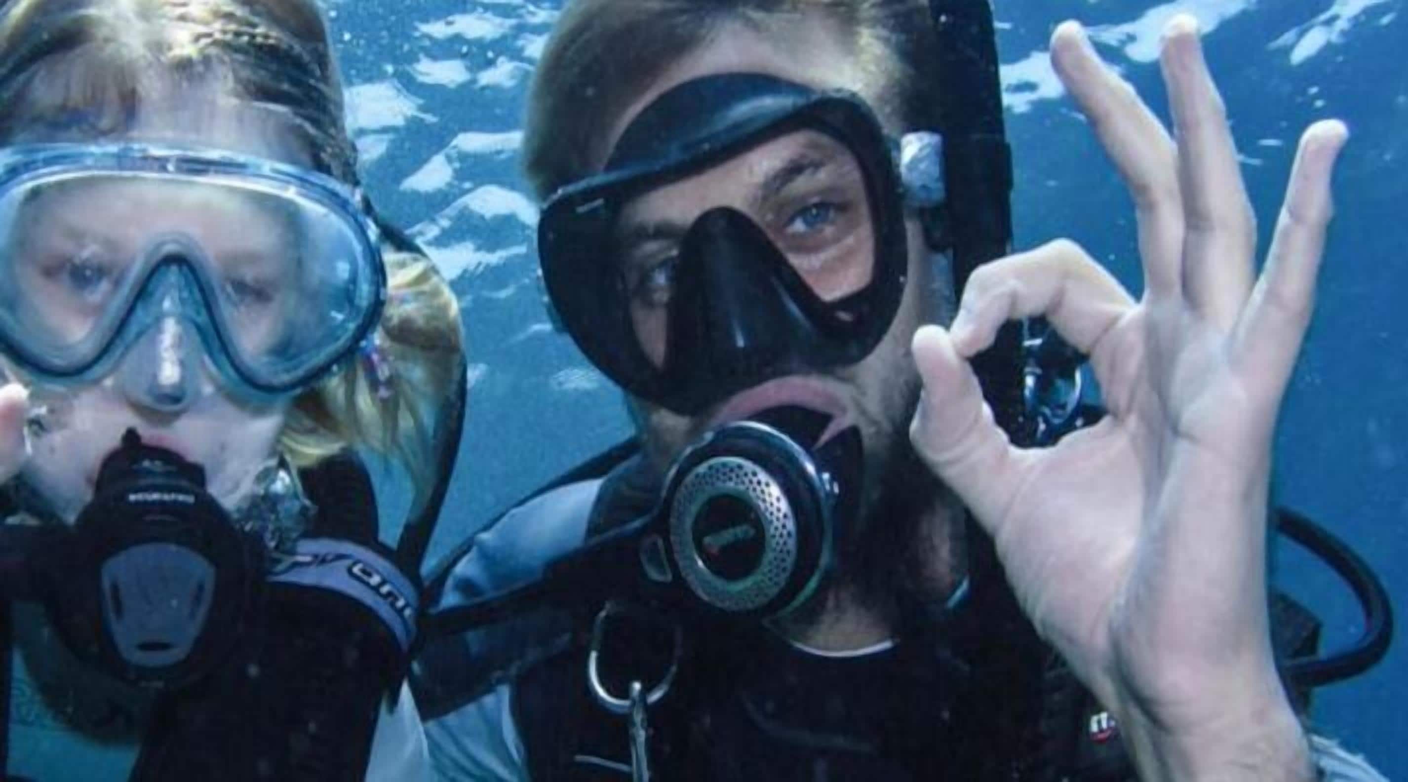 Two people scuba diving with scuba gear, including masks and fins.